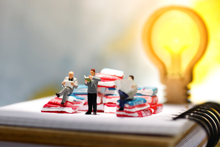 Miniature people reading and sitting on book with lamp idea using as background, education or business concept.の写真素材