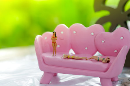 Miniature figures, sexy female in bikini sunbathe on pink sofa, travel concept.の写真素材