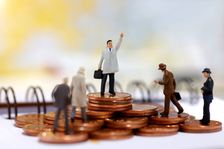 Miniature business people standing on step of coin money. Finance, investment and growth in business concept.の写真素材