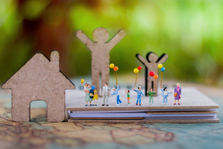 Miniature people with family holding balloon  on the book with  home, happy family day concept.の写真素材