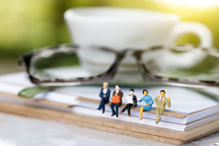 Miniature people reading and sitting on book with glasses using as background, education or business...