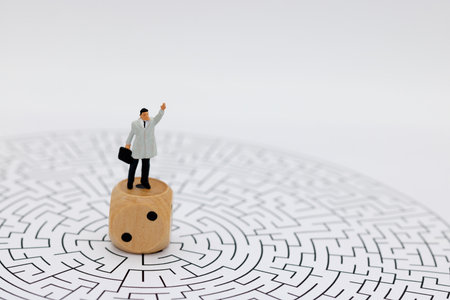 Miniature people: Businessman standing on center of maze with dice. Concepts of finding a solution,...