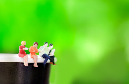 Miniatures people sitting on a cup of coffee with drink coffee and read newspapers. business...