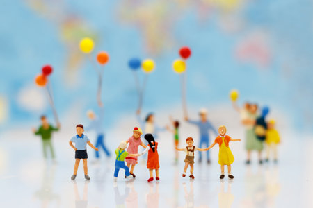Miniature people, family and children with colorful balloons standing in front of house, Family concept.の写真素材