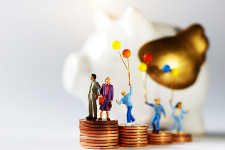 Miniature people with family holding balloon standing on step of coin money.の写真素材