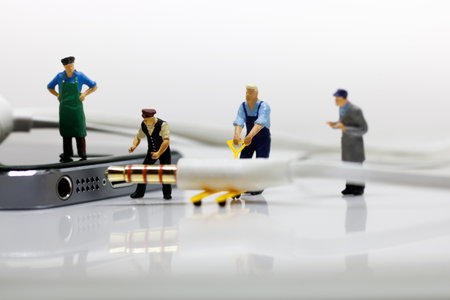 Miniature worker team are doing connected cable earphone jack to the smartphone for listen...
