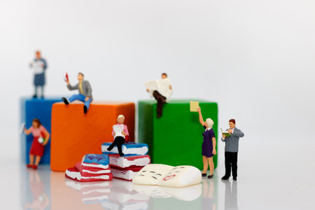 Miniature people reading  book with colorful wooden blocks, education or business concept.の写真素材