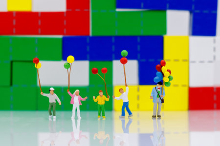 Miniature people, family and children enjoy with colorful balloons, happy family day concept.