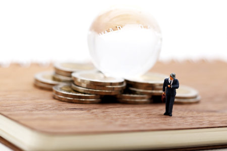 Miniature people: Businessman standing on book with step of coin money and globe.  Concept of Financial and money.の写真素材