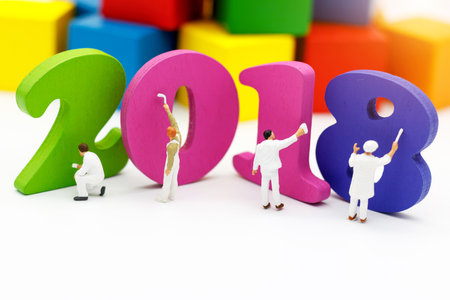 Miniature people: Workers holding a paint brush painting  2018 on a white background.  Happy new...