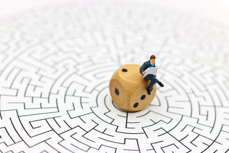 Miniature people: Businessman reading on center of maze. Concepts of finding a solution, problem solving and challenge.の写真素材