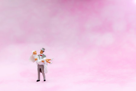 Miniature people: Couple standing on pink background. Concept of marriage, engagement or love.の写真素材