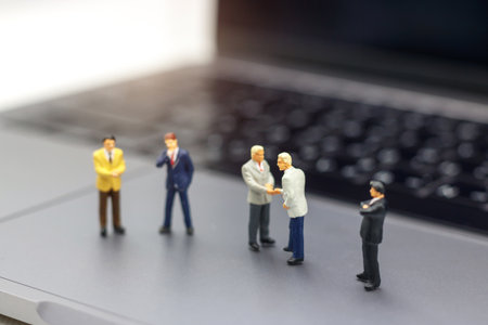Miniature people: Businessman handshake to business success Online on laptop. Commitment, agreement,...