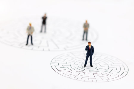 Miniature people: Businessman standing on center of maze and  thinking how to solve this problem. Concepts of finding a solution, problem solving and challenge.の写真素材