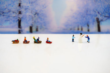 Miniature people: Childrens playing fun with snow slider.