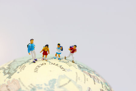 Miniature people: children with school bag play on the globe.の写真素材