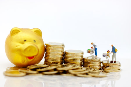 Miniatrue people: Shoppers with shopping cart standing and coins stack. Shopping and business...