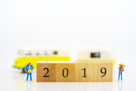Miniature people: Backpacker standing on wooden block with number 2019, travel and business concept.