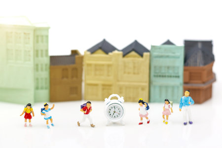 Miniature people: Children standing with clock and school, Education Concept.の写真素材