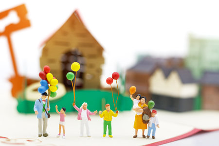 Miniature people: family and children enjoy with colorful balloons and house, happy family day...