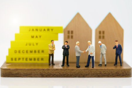 Miniature people: Businessman handshake to business success with wooden houses. Commitment, agreement, investment and partnership conceptの写真素材