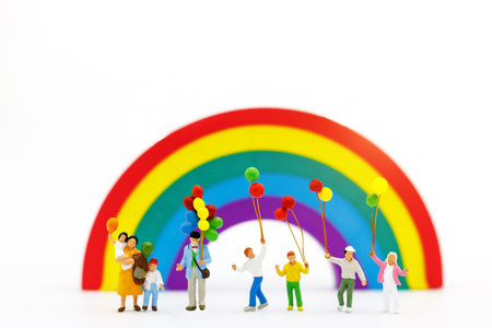 Miniature people: family and children enjoy with colorful balloons on rainbow, happy family day...