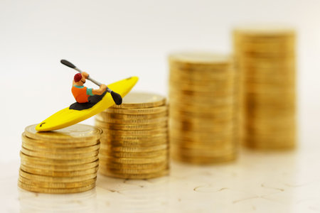 Miniature people Canoe paddle on a gold coins stack. Finance, investment and growth in business concept.の写真素材