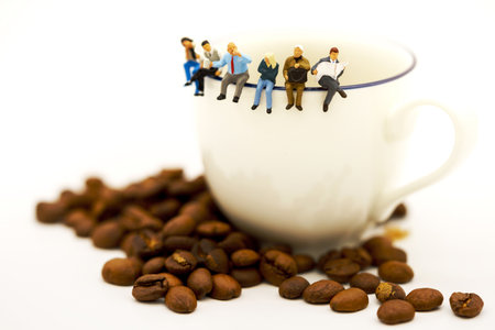Miniature people: business team sitting on cup of coffee with morning news. Coffee time of business concept.の写真素材