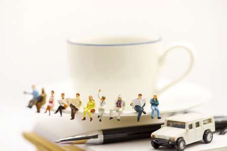 Miniature people: business team sitting on cup of coffee with morning news. Coffee time of business concept.の写真素材