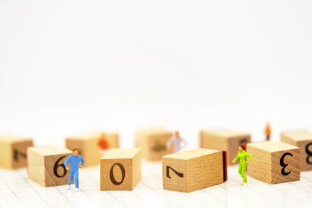 Miniature people running before wooden box number.Business career growth,  achievement, success.,...