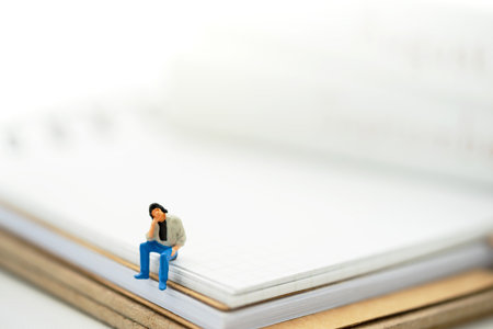 Miniature people: Businessman sitting on the book.の写真素材
