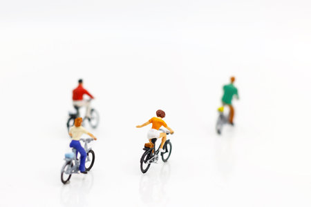 Miniature people enjoy riding a bicycle on white background.