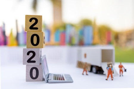 Miniature people: The delivery service of loader with number 2020 on wooden box. Concepts of...