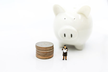 Miniature people: Elderly person standing  with coins stack and piggy bank, Retirement planning concept.の写真素材