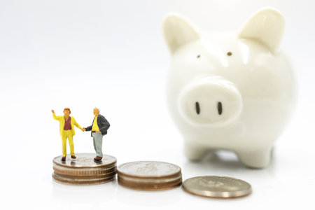 Miniature people: Elderly person standing on coins stack with piggy bank, Retirement planning concept.の写真素材