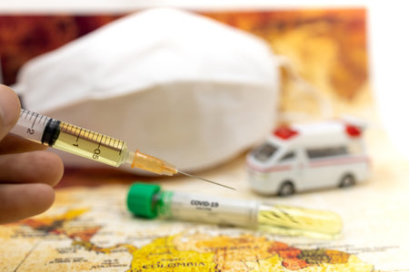 Syringe of COVID-19 vaccine on ambulance car with medical mask and world map background . Vaccine and Healthcare Medical concept.の写真素材