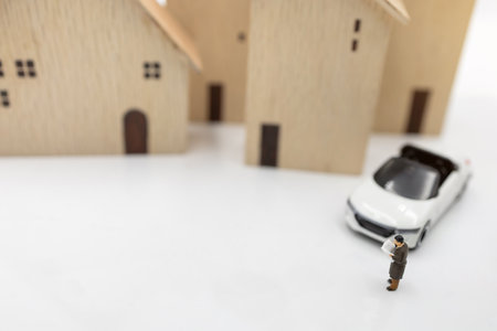 Miniature people:  Businessman reading book with house and car.  Concept of investment in housing and vehicles.の写真素材