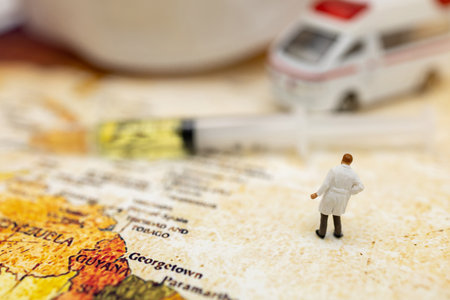 Miniature people stand on world map with ambulance car, medical mask and Syringe of COVID-19 vaccine . Vaccine and Healthcare Medical concept.の写真素材