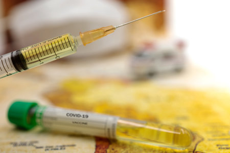 Syringe of COVID-19 vaccine on ambulance car with medical mask and world map background . Vaccine and Healthcare Medical concept.の写真素材