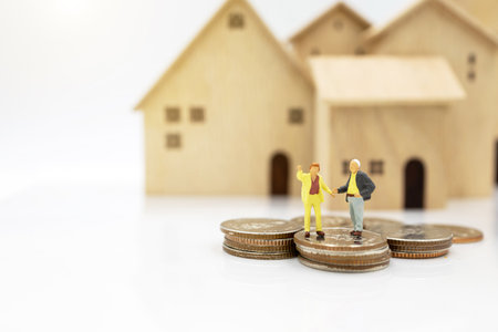 Miniature people: Elderly person standing on coins stack with home, Retirement planning concept.の写真素材