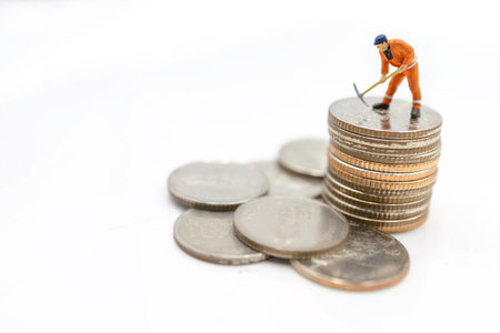 Miniature worker digging on coins stack. Concept of Money and investment.の写真素材