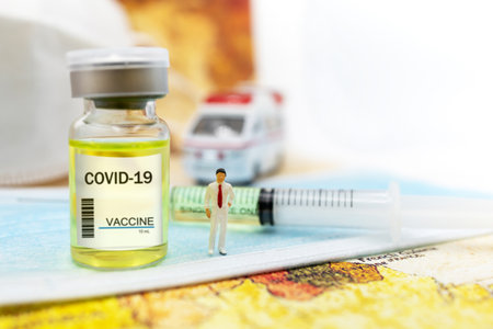 Miniature people : Doctor stand on medical mask with COVID-19 vaccine  and syringe. Vaccine and Healthcare Medical concept.の写真素材
