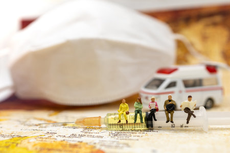 Miniature people sit Syringe of COVID-19 vaccine with ambulance car and medical mask and  . Vaccine and Healthcare Medical concept.の写真素材