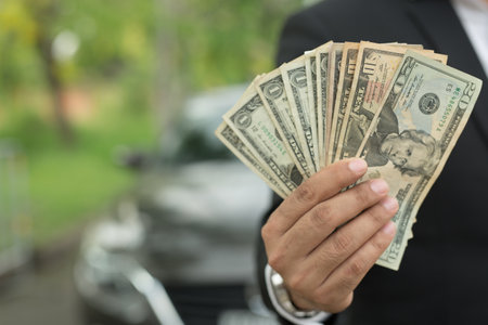 Business man holding money in hand stand front car prepare pay by installments - insurance, loan and...