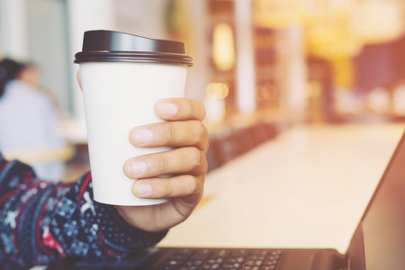 close up hand holding paper cup coffee of take away drinkingの写真素材