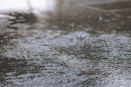 Rain drops in the water heavy on asphalt shade of black shadow and reflection of dark sky in the city. high contrast during autumnの写真素材