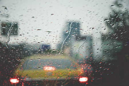 Drops Of Rain Drizzle on the glass windshield in the evening. street in the heavy rain. Bokeh Tail light. soft Focus. Please drive carefully, slippery road. soft focus.の写真素材