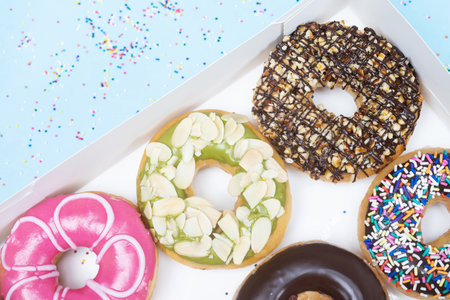 assorted donuts with chocolate frosting, topping sprinkles donuts Colorful variety and Variety of flavors mix of multi colored sweet donuts with frosted sprinkled on blue background. top viewの写真素材