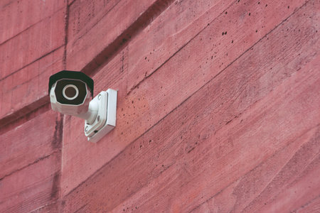 Modern Security IR CCTV camera on a red brick wall building for monitor events in city. Concept Technology of surveillance and monitoring. Leave copy space empty to write a message.の写真素材