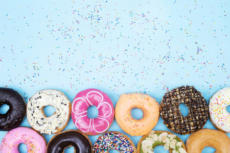 assorted donuts with chocolate frosting, topping sprinkles donuts Colorful variety and Variety of flavors mix of multi colored sweet donuts with frosted sprinkled on blue background.の写真素材